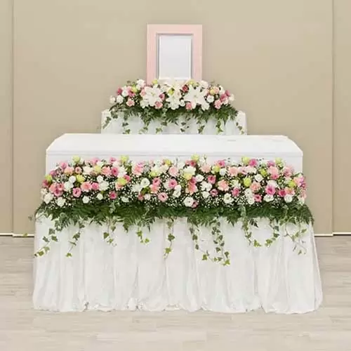 ベージュの背景に白と赤色が基調とした花がメインの祭壇
