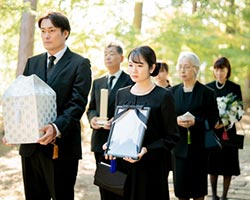 家族が故人様の遺影と遺骨を抱えて歩いている場面